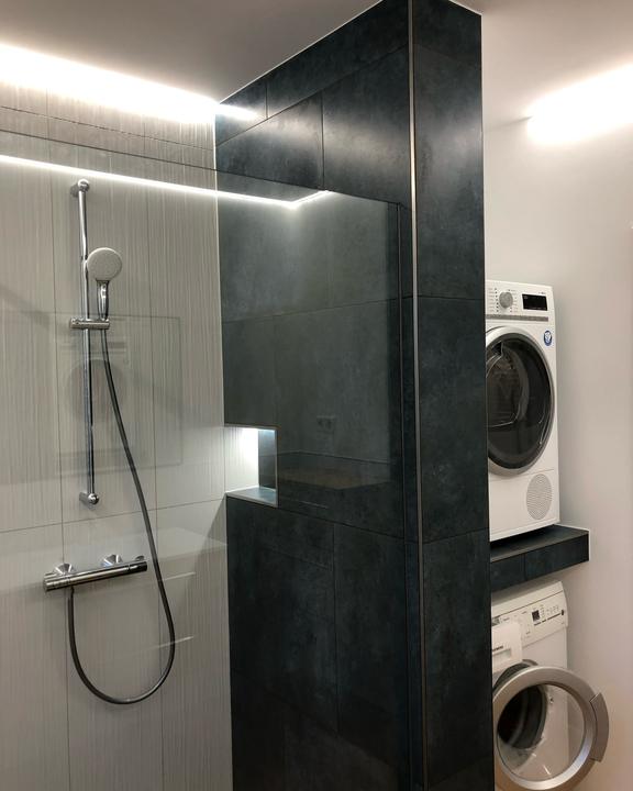 Walk-in-Dusche mit dunkler Fliesensäule und LED-Licht